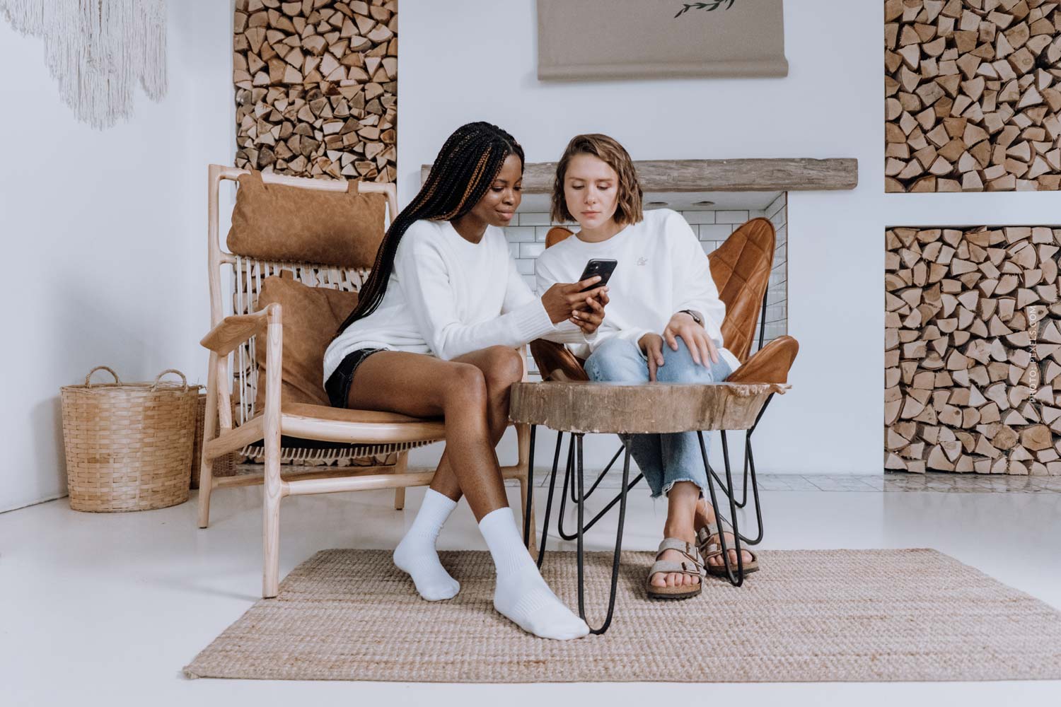 social-engagement-two-women-sitting-on-chairs-carpet-smartphone